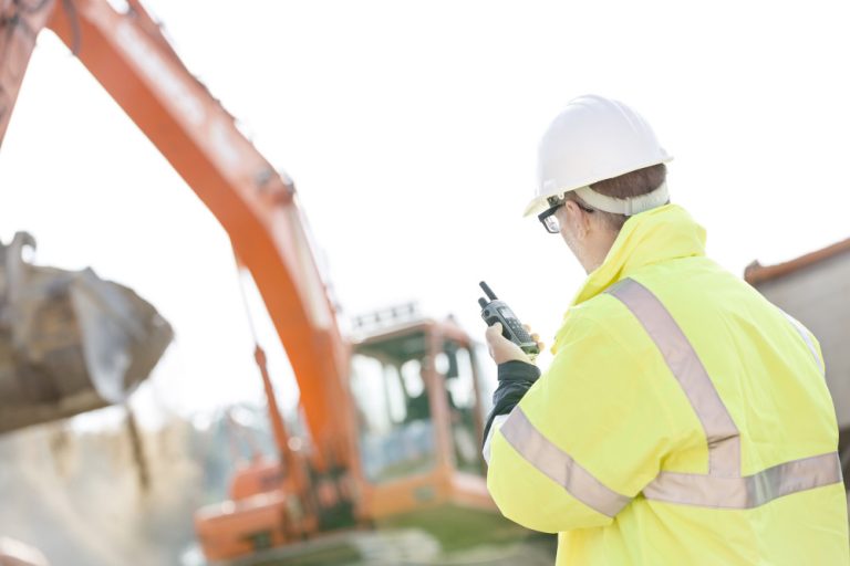 Supervisor,Using,Walkie-talkie,At,Construction,Site,Against,Clear,Sky